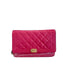 A bright pink quilted leather clutch wallet with a gold-tone interlocking CC clasp, displayed in front of a black Chanel box on a light beige surface.