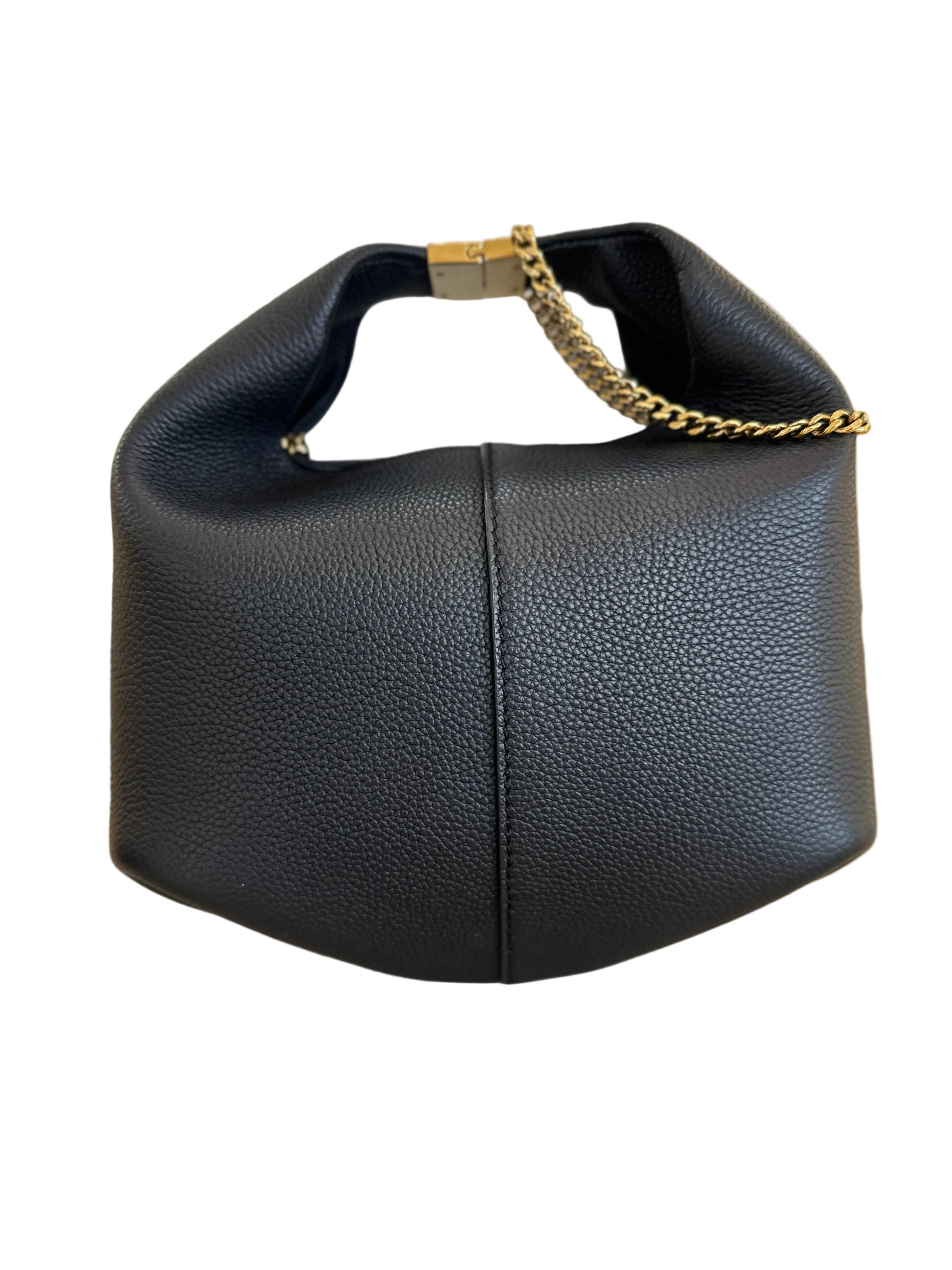 A black pebbled leather shoulder bag with a gold chain handle accent, displayed on a light beige surface in front of a white box inside a store.