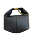 A black pebbled leather shoulder bag with a gold chain handle accent, displayed on a light beige surface in front of a white box inside a store.